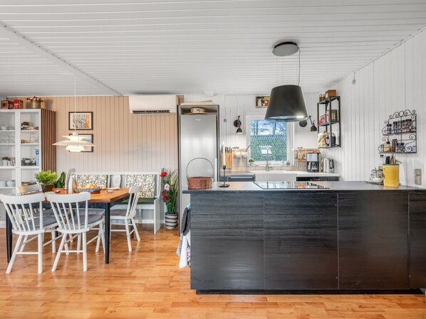 Une cuisine moderne dotée d’un îlot central, de planchers en bois et d’un coin repas avec des chaises blanches.