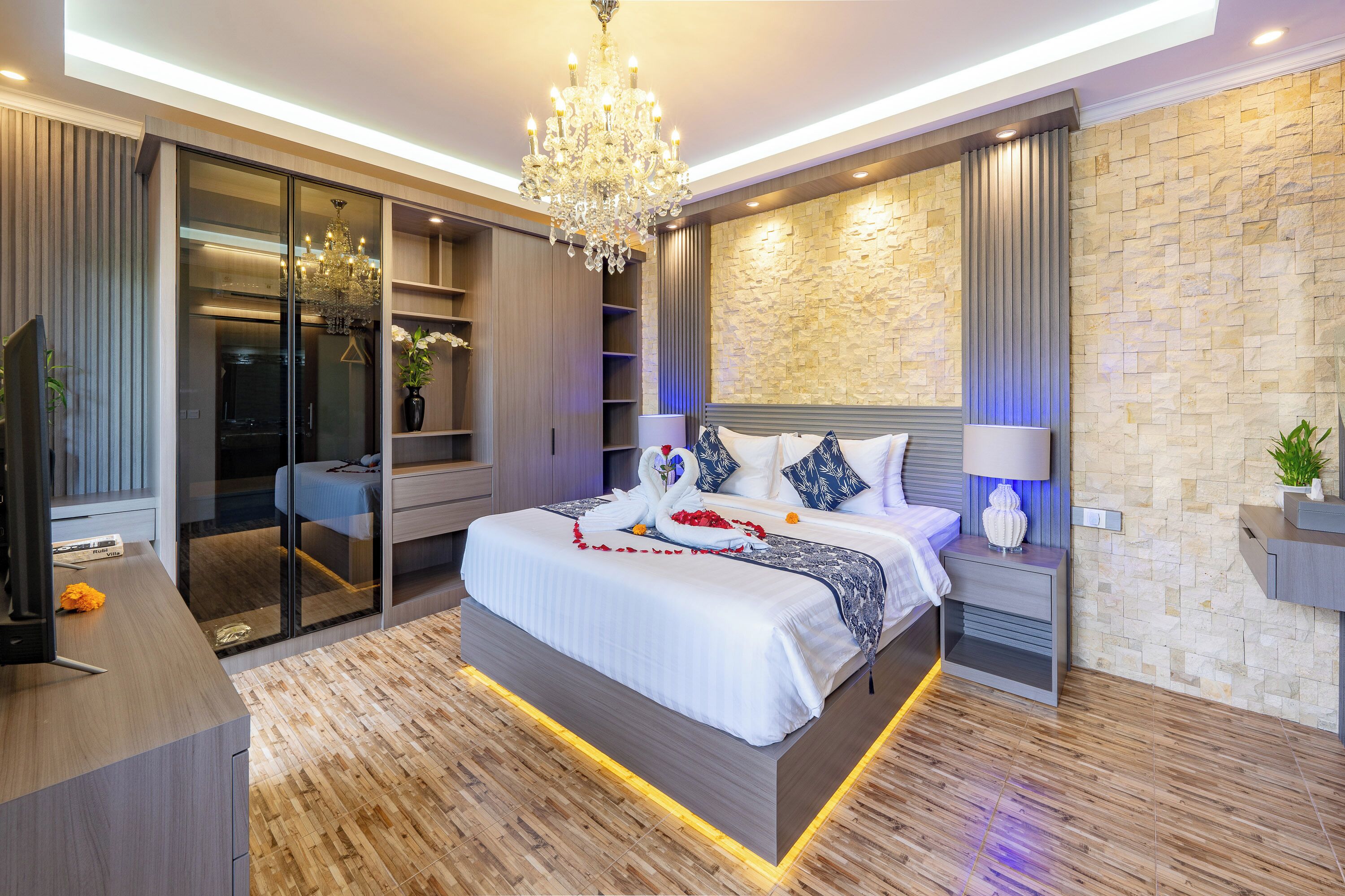 A modern bedroom with a large bed, built-in wardrobe, and a chandelier.