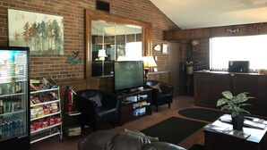 A living room with a brick wall, a television, a refrigerator, and a coffee table. - Country Lodge inn (Harmony)