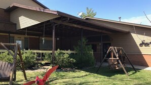 A building with a covered porch, a swing set, and a bird sculpture. - Country Lodge inn (Harmony)