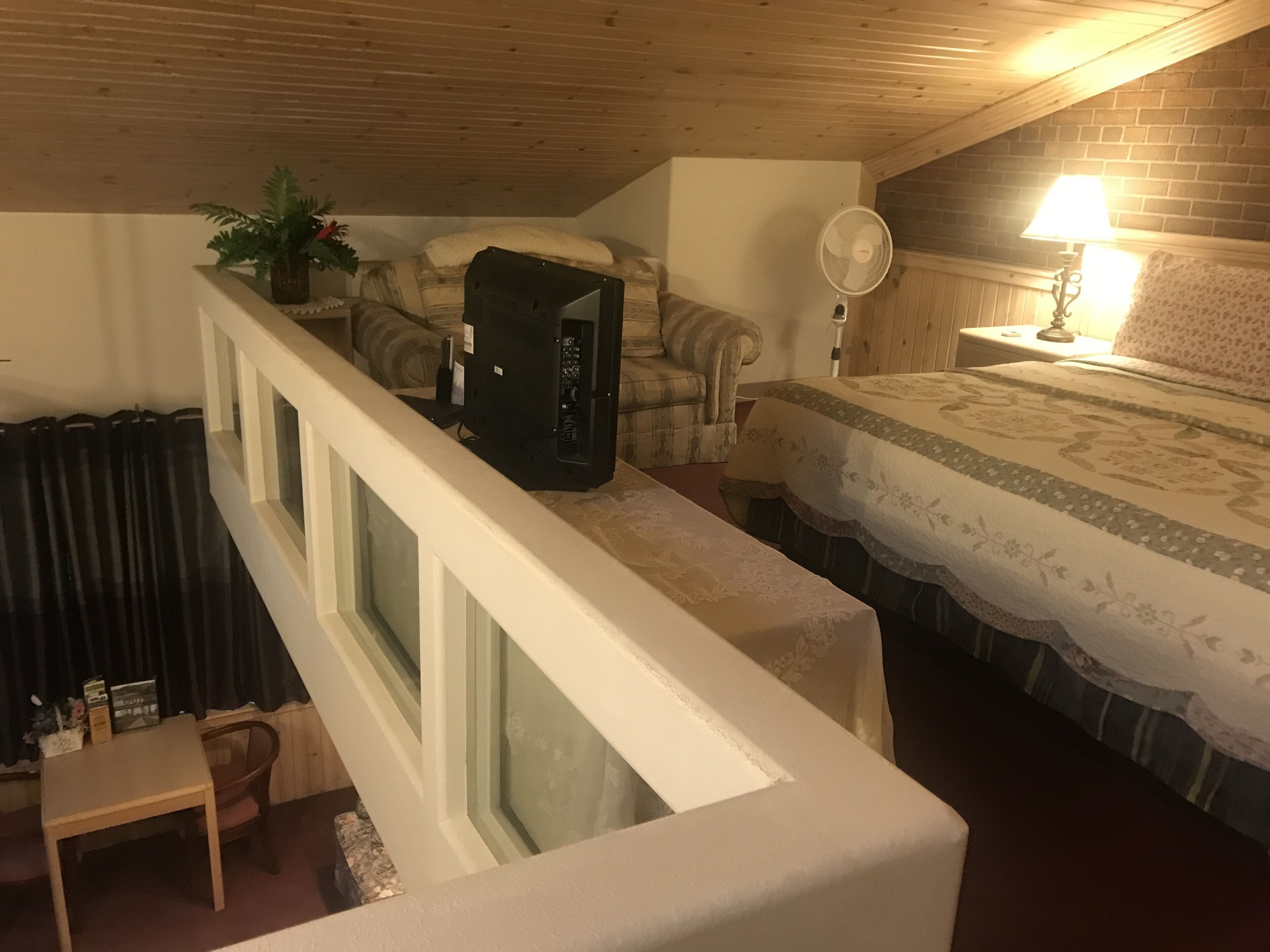 Una camera da letto con un letto, una sedia, una scrivania, un termosifone, una ventola e una finestra.
