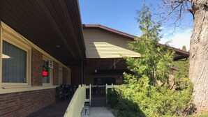 A building with a covered porch, a brick exterior, and a white fence. - Country Lodge inn (Harmony)