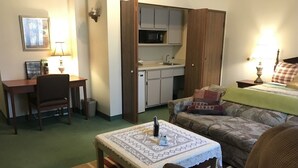 A compact living space with a kitchenette, a dining area, and a sofa. - Country Lodge inn (Harmony)