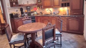 A kitchen with wooden cabinets, a round dining table with chairs, a coffee maker, and a sink. - Kauris Apartament (Gdańsk)