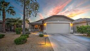 A residential house with a garage, driveway, and landscaped garden. - Mid Century Themed Home on the Golf Course (San Tan Valley)