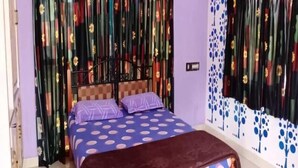 A bedroom with a bed, curtains, and a wall with a tree pattern. - Chandrika Guest House  (Paderu)