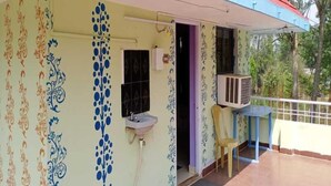 A house with a colorful exterior, a small porch, and a window with a decorative grille. - Chandrika Guest House  (Paderu)