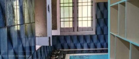 A kitchen with blue and white tiles, a gas stove, and a window with decorative glass panes.