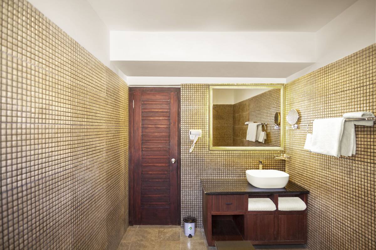 A bathroom with a wooden door, a sink with a mirror, and a towel rack.