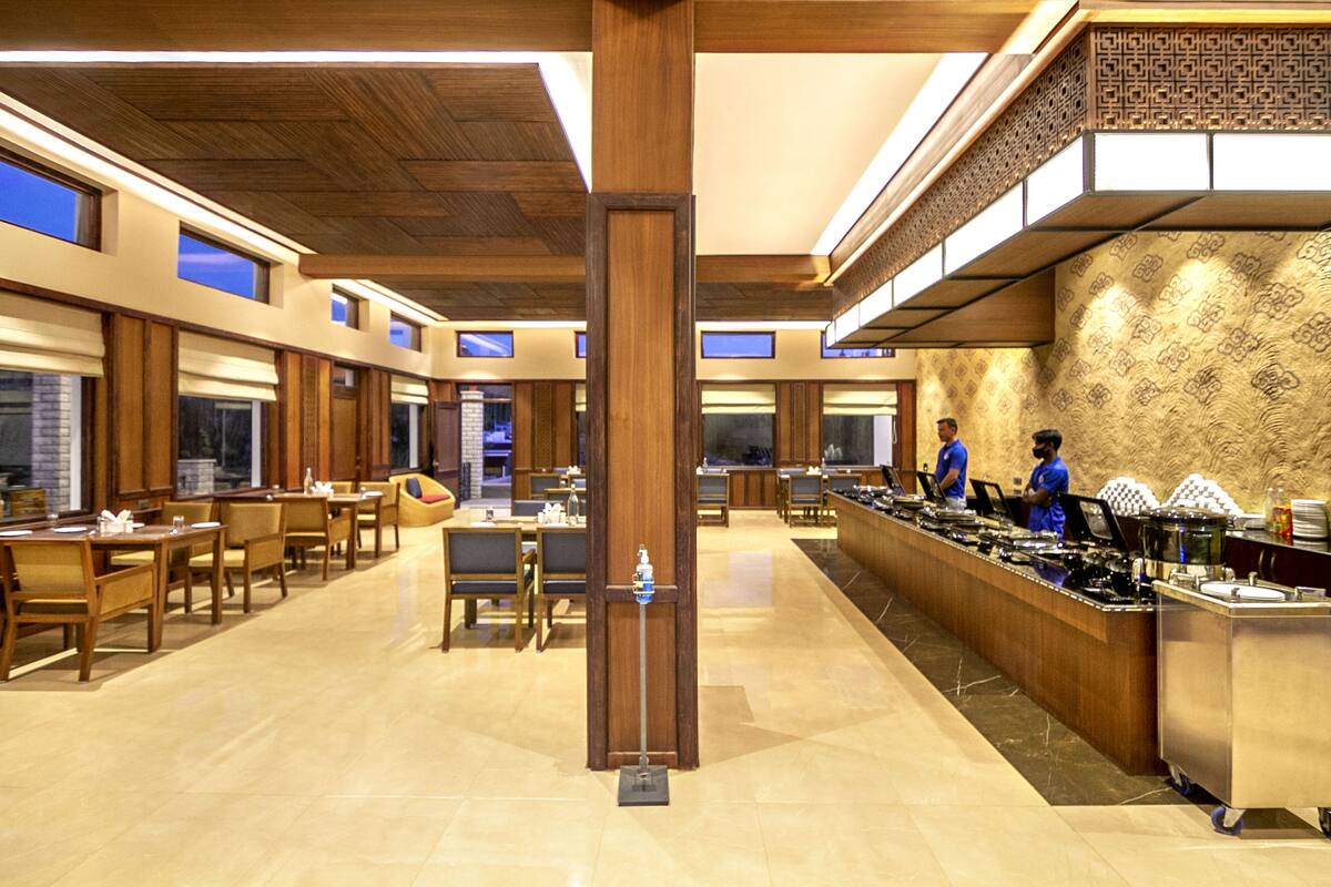 A spacious restaurant with wooden furniture, a buffet counter, and a patterned wall.