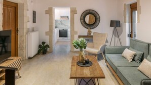 A modern living room with a wooden table, a green sofa, and a TV. - Fillio luxury villa (Αδελιανός Κάμπος)