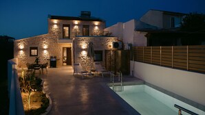 A modern house with a swimming pool, stone walls, and outdoor seating. - Fillio luxury villa (Αδελιανός Κάμπος)