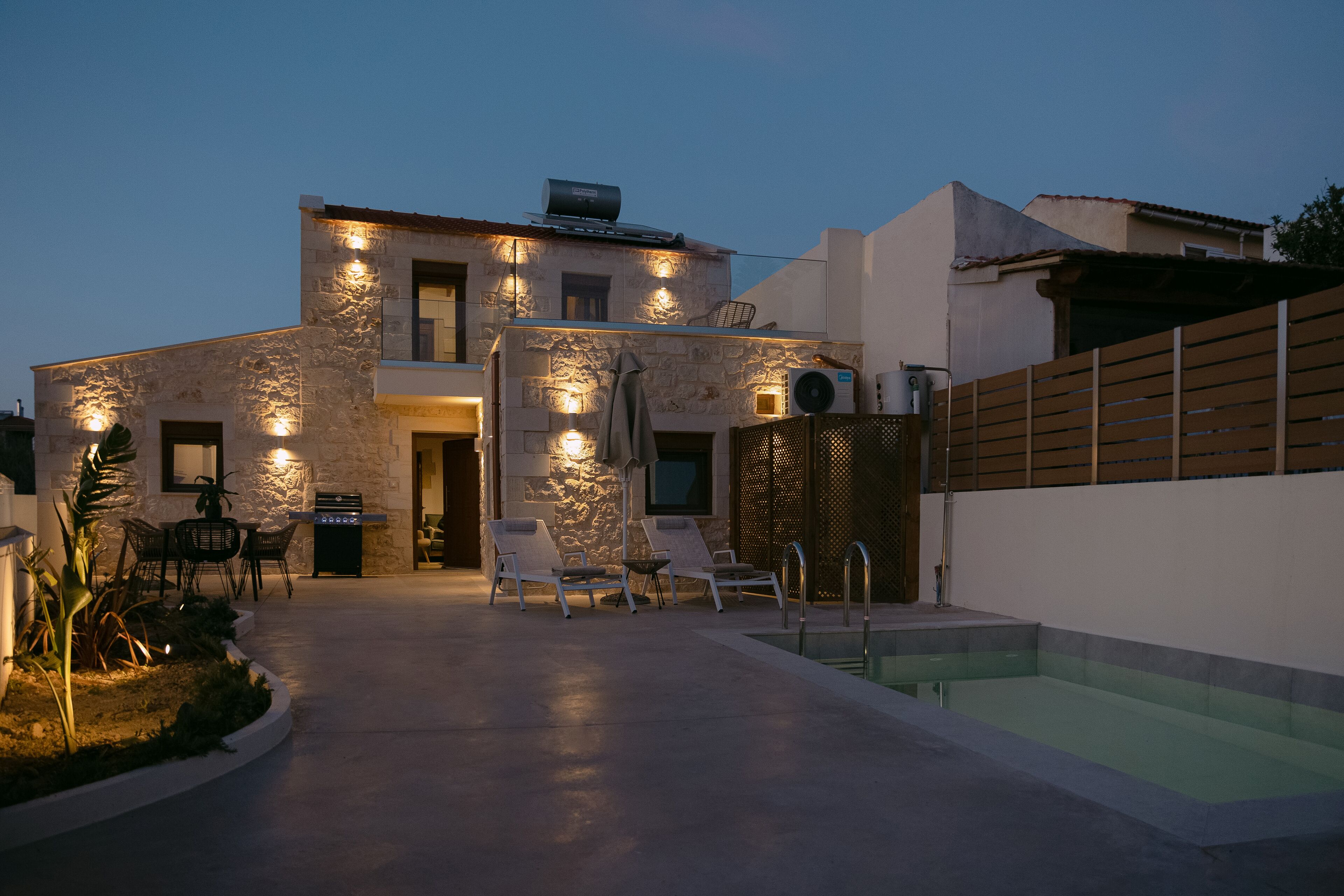 Uma casa moderna com fachada de pedra, piscina e área de estar ao ar livre.