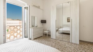 A bedroom with a bed, a dresser, a TV, and a sliding door to a balcony. - 3795 Joy R - Appartamento 3 by Barbarhouse (Manduria)