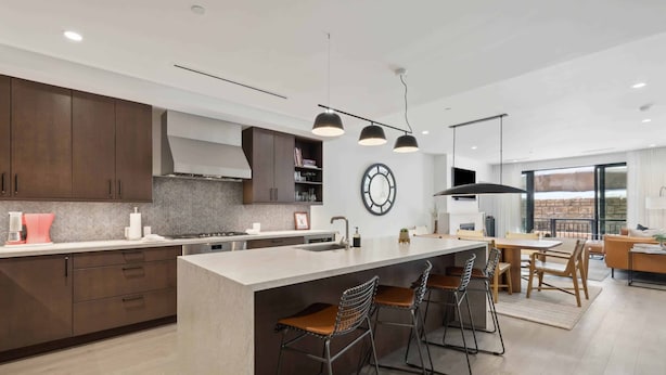 Una cocina moderna con una isla grande, taburetes de bar y un comedor con mesa y sillas.