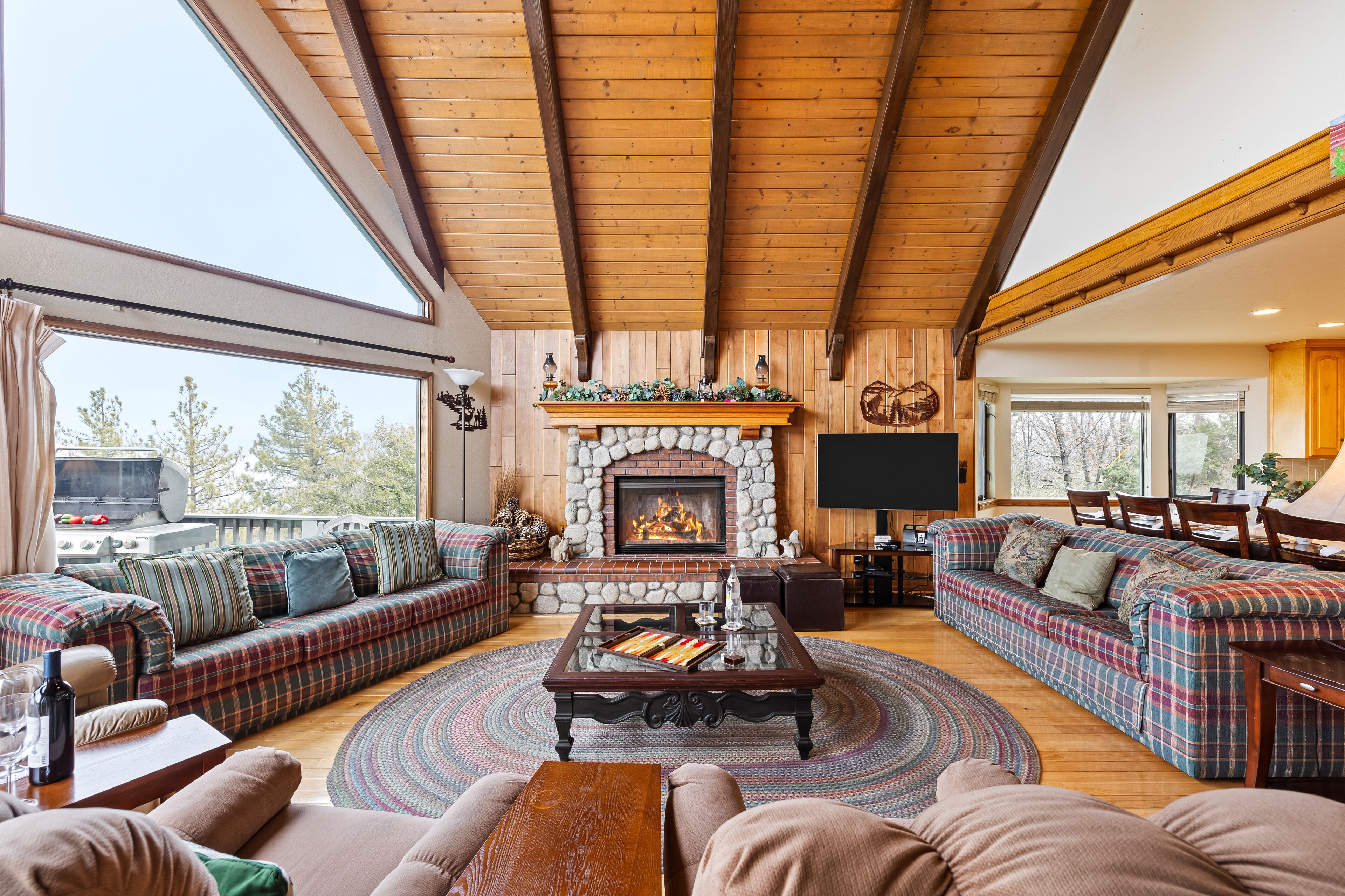 A cozy living room with a stone fireplace, large windows, and a comfortable seating area.