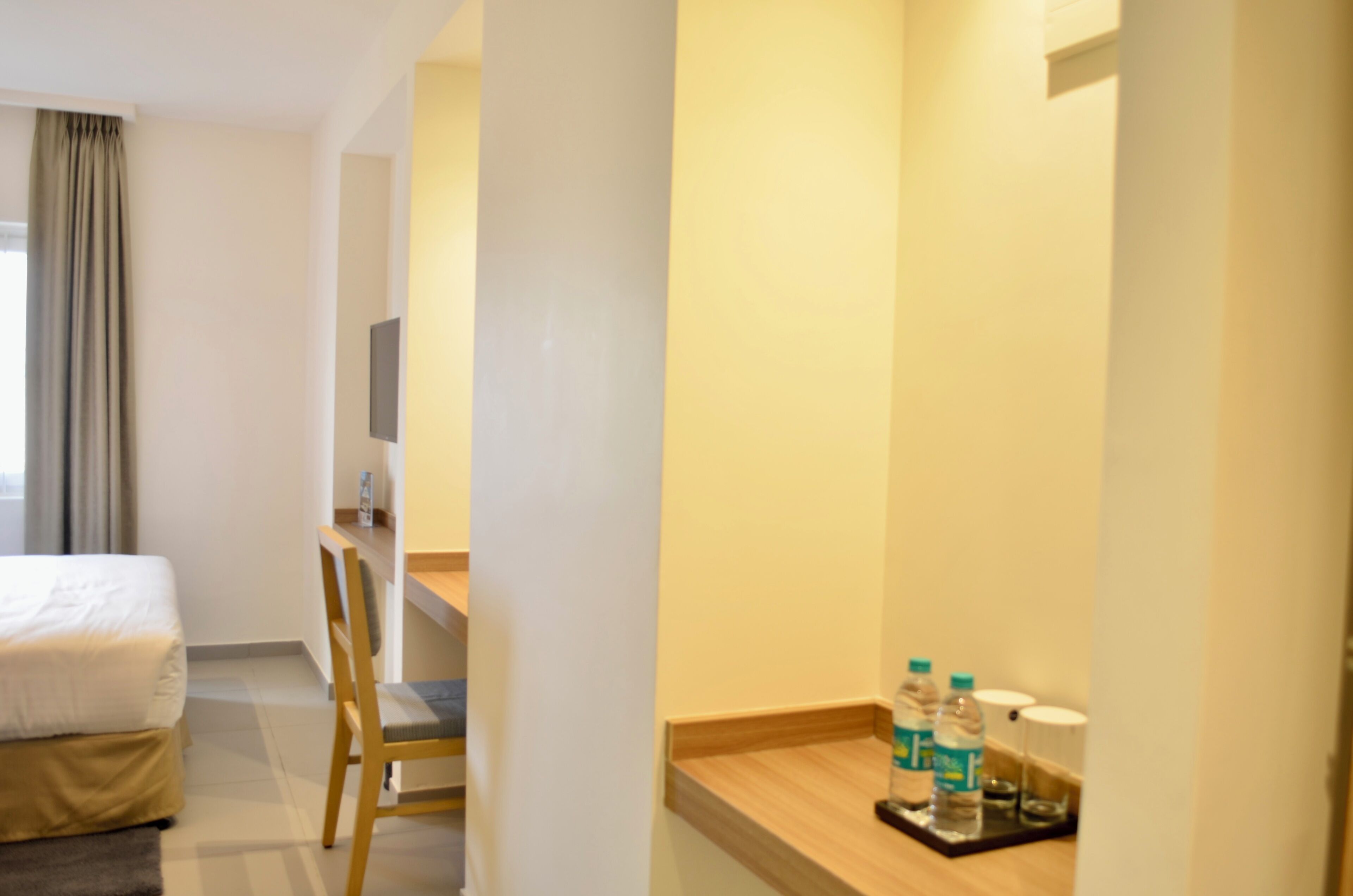 Habitación de hotel con cama, escritorio, silla y una mesita con botellas de agua.