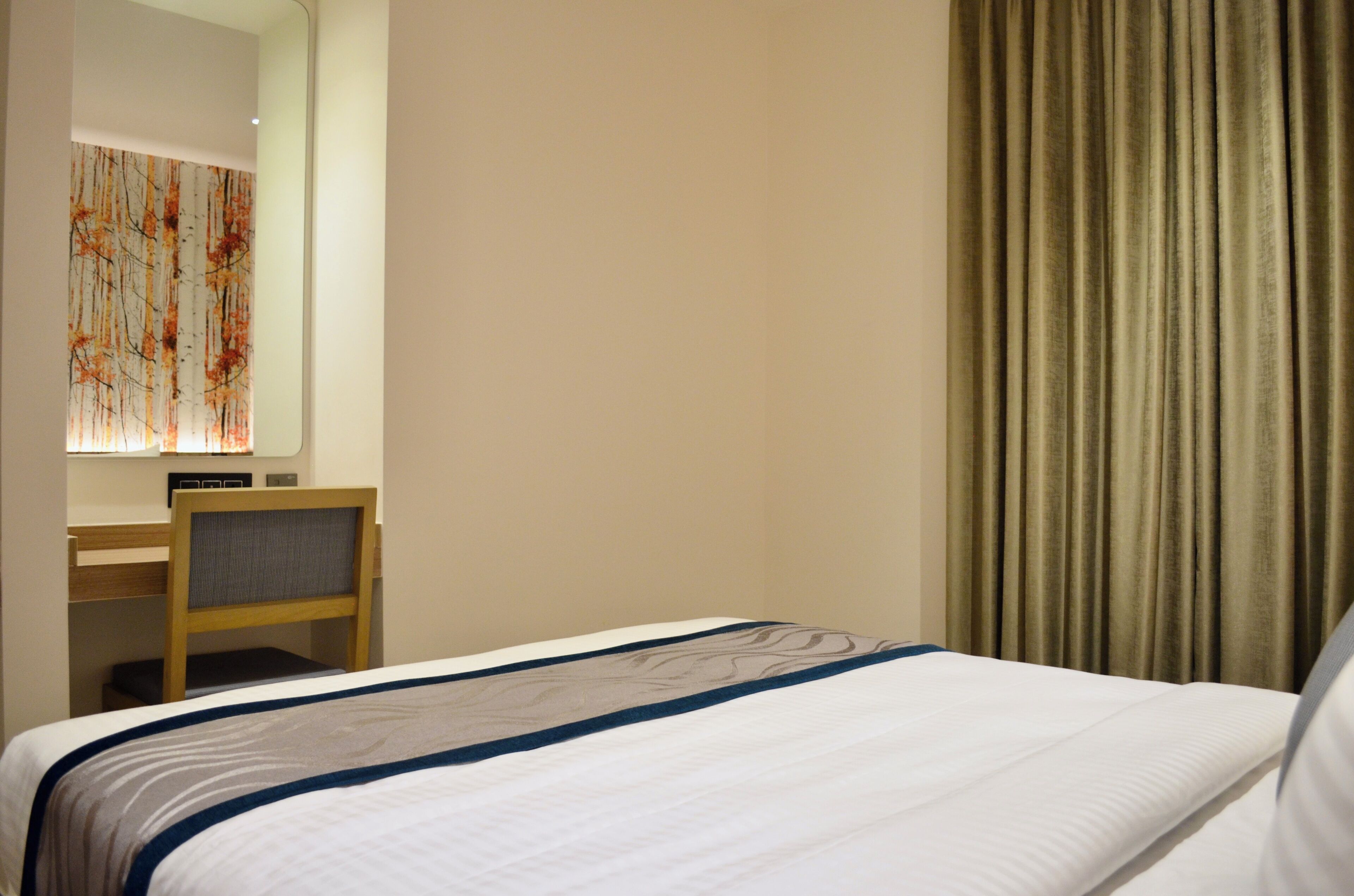 A hotel room with a bed, a desk, and a chair.