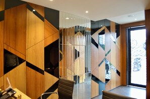 A modern office space with geometric wooden paneling, a glass partition, and a staircase. - City Lake Hotel  (Bengaluru)