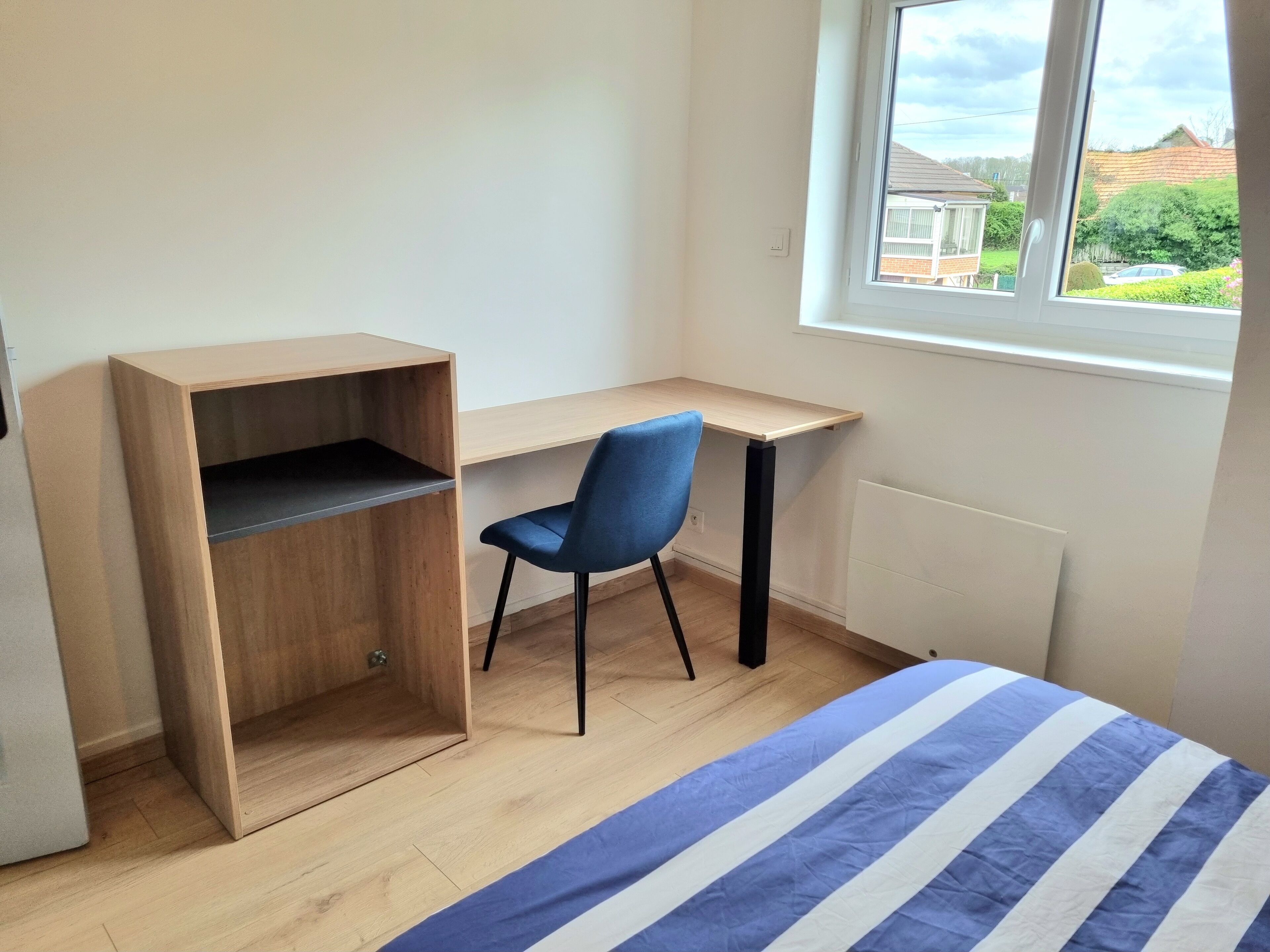 A bedroom with a bed, a desk, and a chair.
