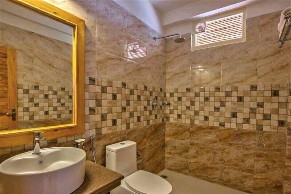 A bathroom with a marble wall, a sink, a toilet, and a shower area.