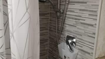 Un área de ducha con diseño moderno, que incluye un cabezal de ducha, ducha de mano y dispensador de jabón.