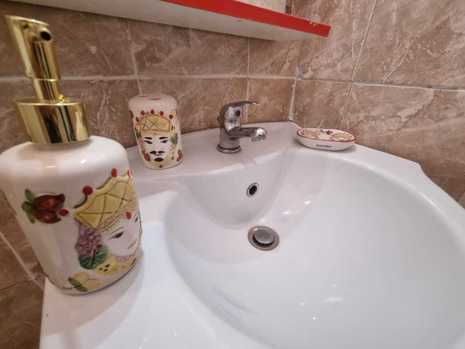A bathroom sink with a gold faucet, a decorative soap dispenser, and a small dish.