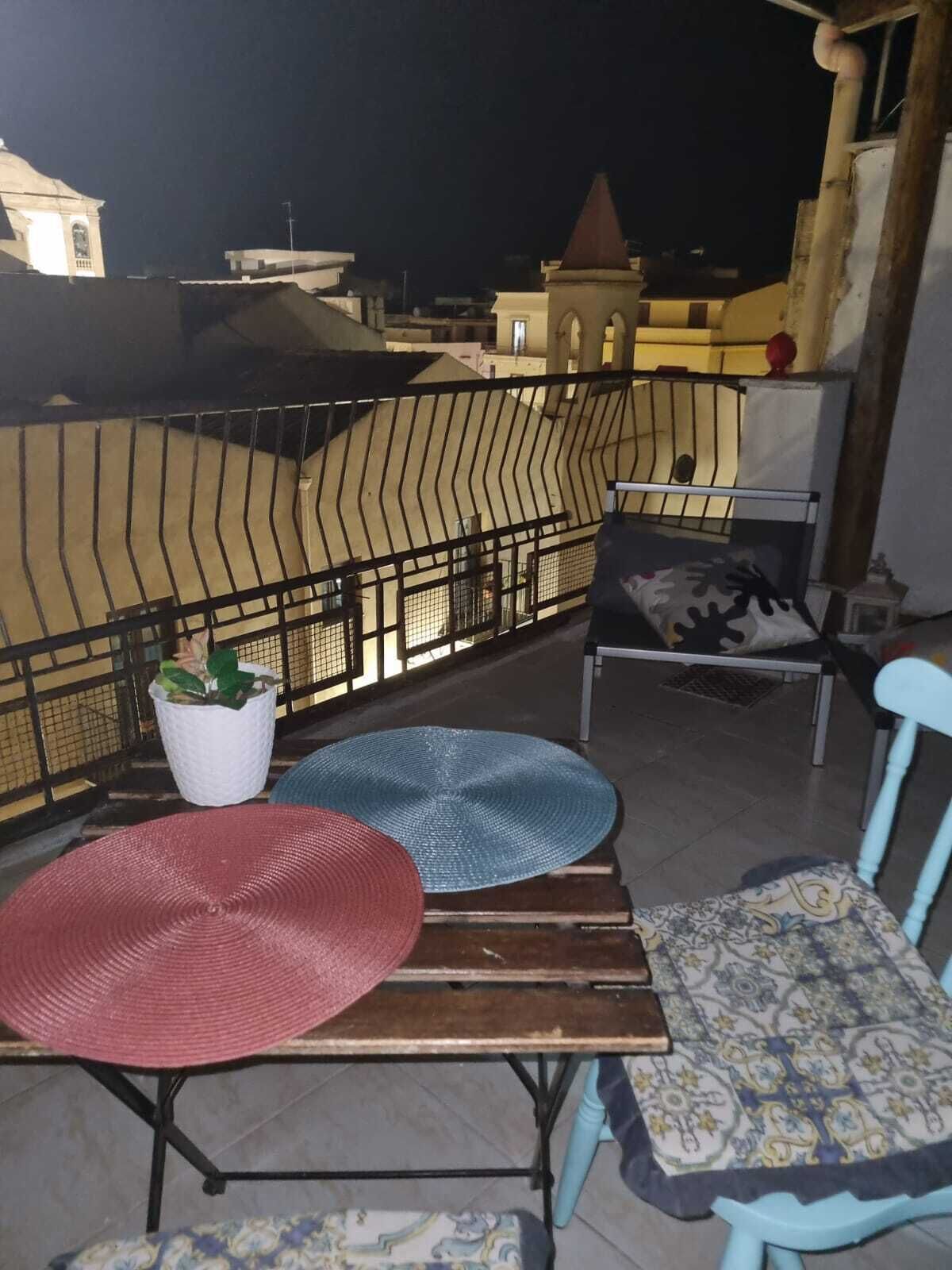 Een balkon met een tafel, twee stoelen en een bloempot.