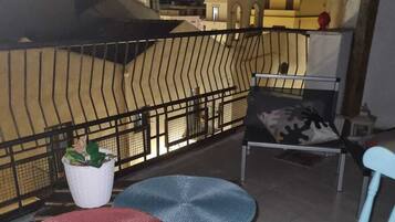Een balkon met een tafel, twee stoelen en een bloempot.