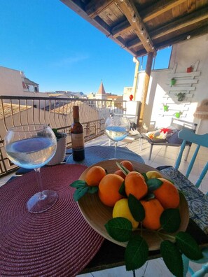 A balcony with a table set for two, featuring a bottle of wine, two glasses, and a bowl of oranges. - La Gorgone city center apartments (Casteldaccia)