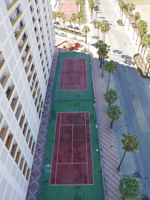 A high-rise building with two tennis courts on the ground floor, surrounded by palm trees and a parking area. - EUROMAR, ESC-6, 15º-45 (Cullera)