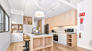 Eine moderne Küche mit Holzausstattung, einer zentralen Kochinsel mit Sitzgelegenheiten, einer Mikrowelle und einer Kaffeemaschine.