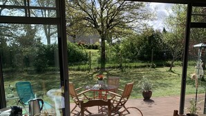 A dining area with a table set for four, surrounded by chairs, with a garden view through large windows. - A guest room for rent (possibility of renting 2 rooms) (Vienne en val)