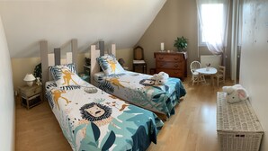 A bedroom with two beds, a dresser, a chair, a table, and a basket. - A guest room for rent (possibility of renting 2 rooms) (Vienne en val)