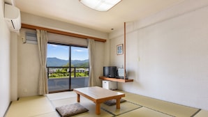 A room with tatami flooring, a wooden table, a TV on a shelf, and a view of mountains through a sliding door. - SEMINAR PLAZA ROYAL FUJI (Fujikawaguchiko)