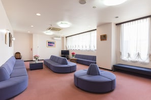 A modern living room with a sectional sofa, ottoman, and a flat-screen TV. - SEMINAR PLAZA ROYAL FUJI (Fujikawaguchiko)