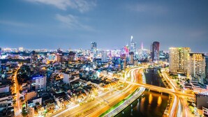 A nighttime cityscape with illuminated buildings, a river, and a multi-lane highway. - Fusion RiverGate Apart Infinity Pool (Ho Chi Minh City)