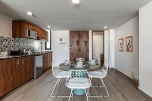 Enjoy meals around the central round table in this kitchen and dining area, featuring a microwave and various appliances.