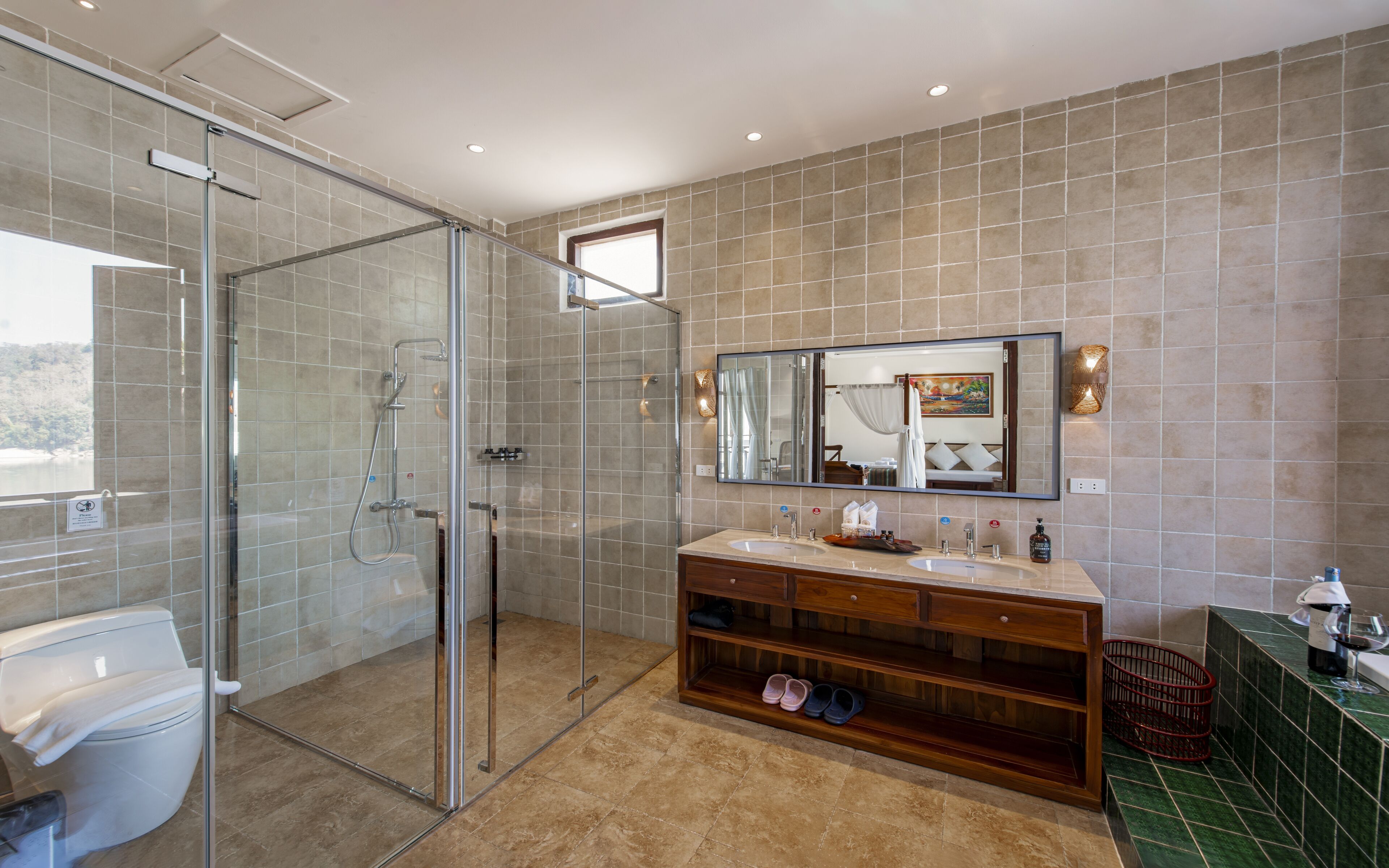 A modern bathroom with a glass-enclosed shower, a large mirror, and a vanity with a sink and storage.