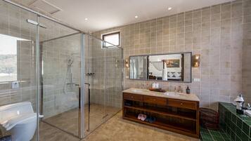 A modern bathroom with a glass-enclosed shower, a large mirror, and a vanity with a sink and storage.