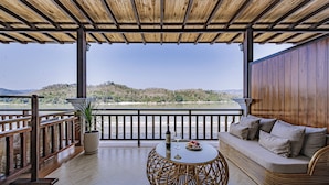 A covered outdoor seating area with a view of a lake and hills. - Relaxful Hotel (Luang Prabang)