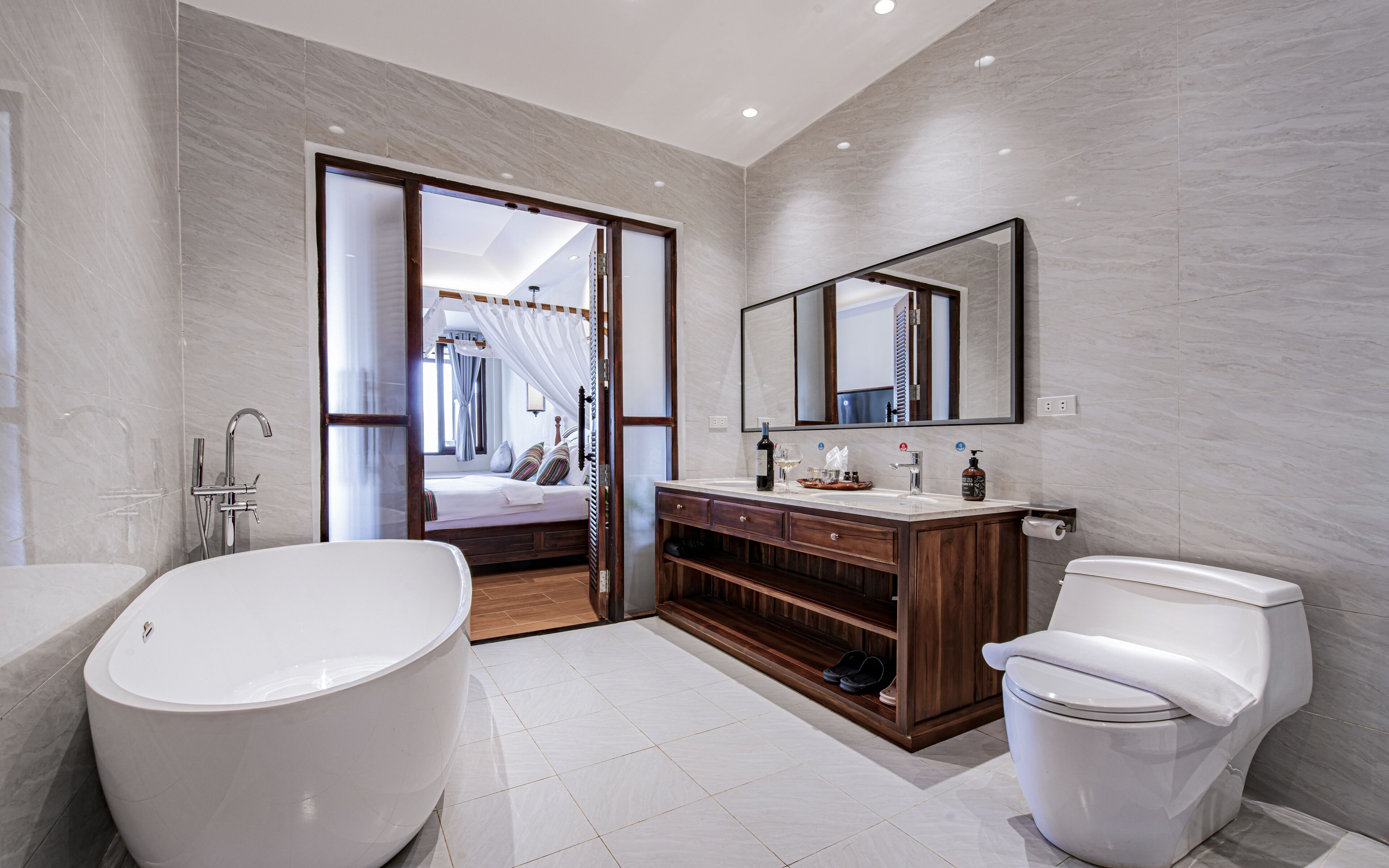 Ein modernes Badezimmer mit einer freistehenden Badewanne, einem Holzwaschtisch, einem großen Spiegel und einer Toilette.