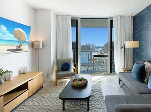 A modern hotel room with a balcony, a large window, a sofa, a desk, and a wall map. - Spectacular Resort: Designed Luxe, Amazing View (Hallandale Beach)