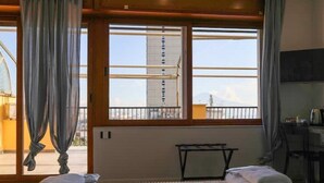 A hotel room with a bed, a small table, and a view of a building through the window.