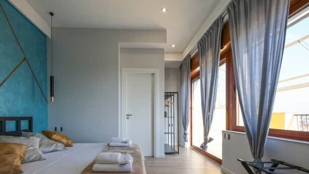A modern hotel room with a large bed, a desk, and a view of the city.