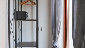 A room with a metal shelving unit, a power outlet, and a curtain tied at the bottom.