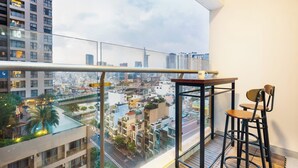 A balcony with a city view, a table, and two chairs. - Fusion Riverside Apart Near Ben Thanh (Ho Chi Minh City)