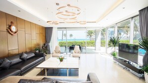 Ein modernes Wohnzimmer mit Sofa, Couchtisch und Fernseher mit Blick auf einen Pool und den Ozean.