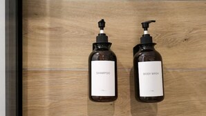 Two bottles of shampoo and body wash on a wooden surface.