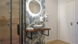 A bathroom with a wooden floor, a white sink with a mirror above it, a towel rack, and a toilet.